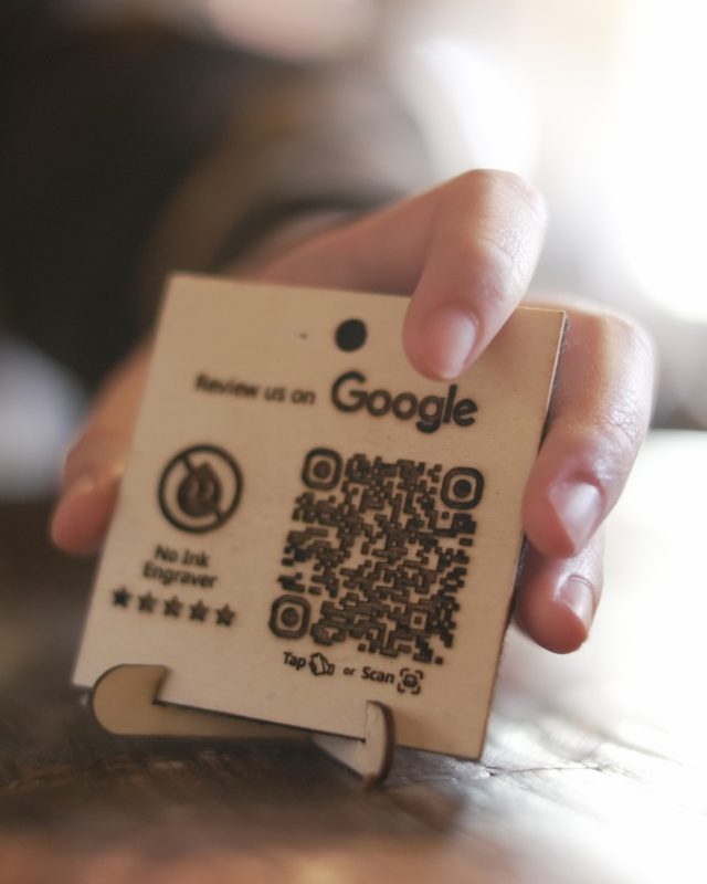 Hand holding a No Ink NFC and QR review plaque